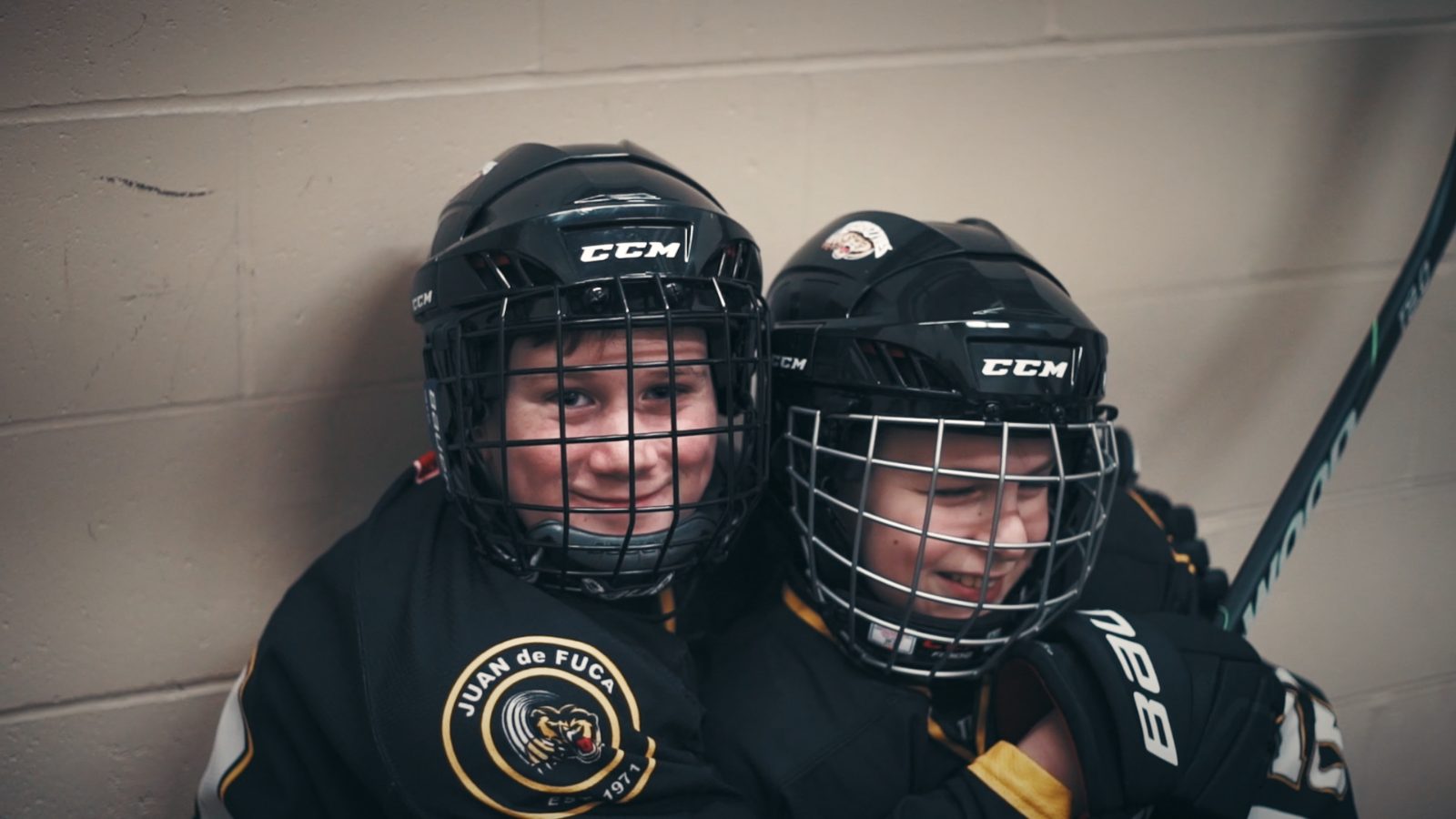 Two young players in helmets sharing a moment on the ice